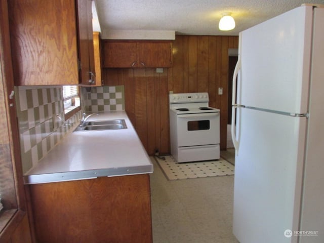 kitchen with a sink, light countertops, light floors, white appliances, and brown cabinetry