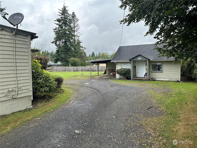 exterior space featuring crawl space, fence, driveway, a shingled roof, and an attached carport