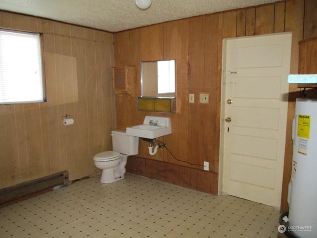 bathroom with a baseboard radiator, wooden walls, toilet, tile patterned floors, and water heater