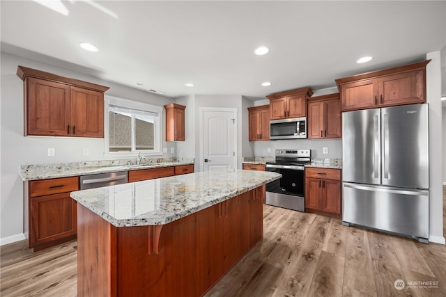 kitchen with a kitchen island, stainless steel appliances, sink, light wood-type flooring, and a breakfast bar area