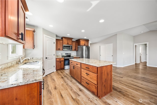 kitchen with appliances with stainless steel finishes, a center island, light hardwood / wood-style floors, sink, and light stone counters