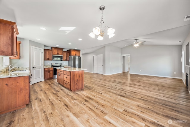 kitchen featuring appliances with stainless steel finishes, a center island, light hardwood / wood-style floors, sink, and hanging light fixtures