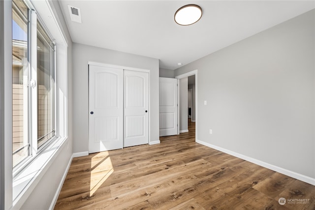 unfurnished bedroom featuring a closet, hardwood / wood-style flooring, and multiple windows