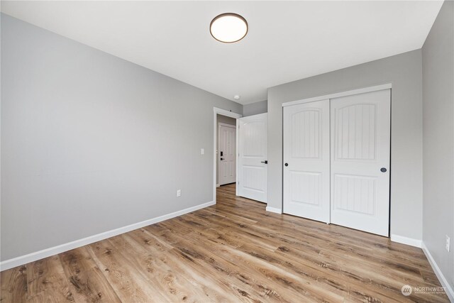 unfurnished bedroom featuring light wood-type flooring and a closet