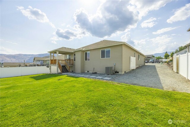 rear view of property with a mountain view, a lawn, and central air condition unit