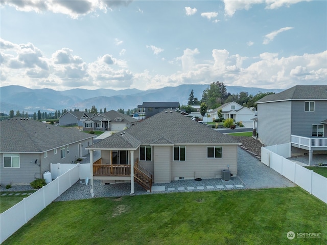 back of property with a deck with mountain view, central air condition unit, and a yard