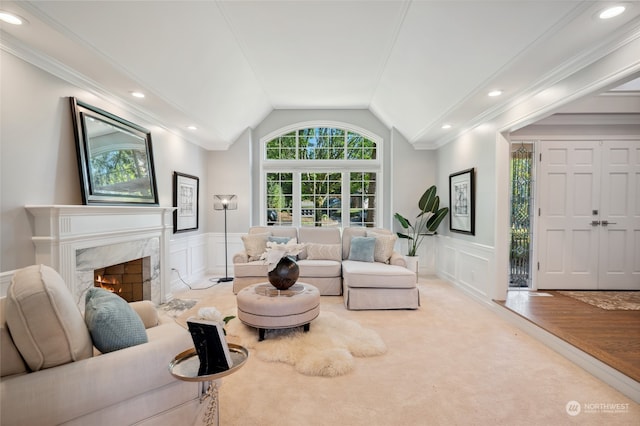 living room featuring light hardwood / wood-style floors, vaulted ceiling, ornamental molding, and a fireplace