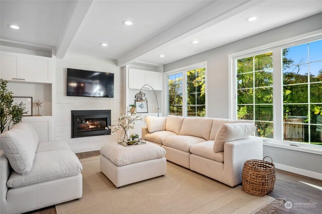 living room with light wood-type flooring, a fireplace, and beamed ceiling