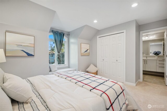 carpeted bedroom with ensuite bath, sink, and a closet