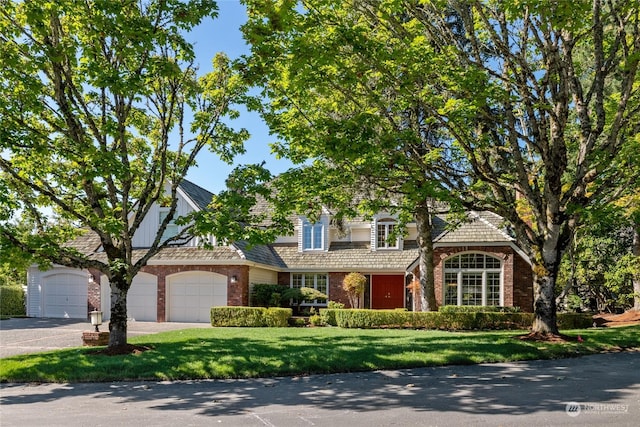 view of front of property with a garage, aphalt driveway, a front lawn, and brick siding