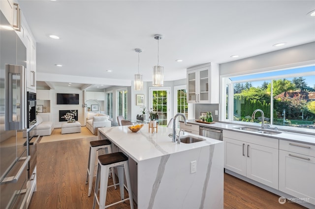 kitchen featuring an island with sink, dark hardwood / wood-style flooring, sink, and white cabinetry