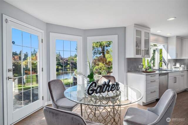 dining area with dark wood-type flooring, a healthy amount of sunlight, sink, and a water view