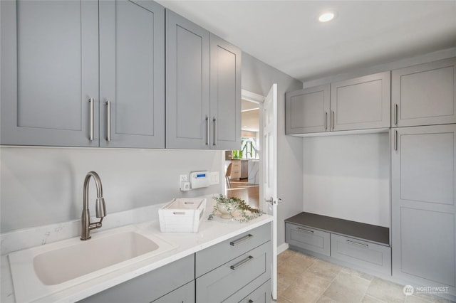 kitchen featuring recessed lighting, light countertops, a sink, and gray cabinetry