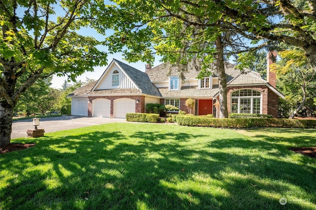 view of front of house with driveway, brick siding, a chimney, and a front yard