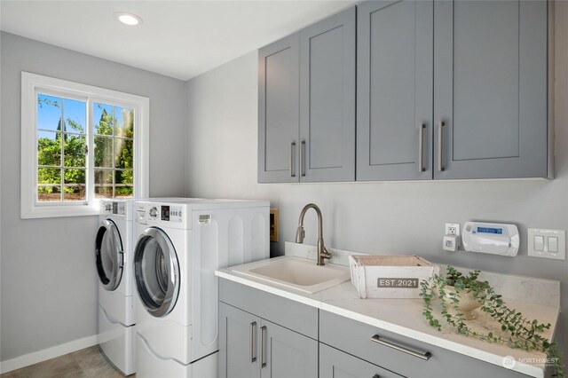 clothes washing area featuring light tile patterned floors, cabinets, washer and dryer, and sink