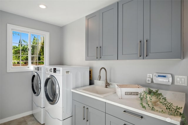 washroom featuring recessed lighting, cabinet space, washing machine and dryer, a sink, and baseboards