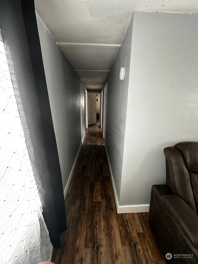 hallway featuring dark wood-type flooring and a textured ceiling