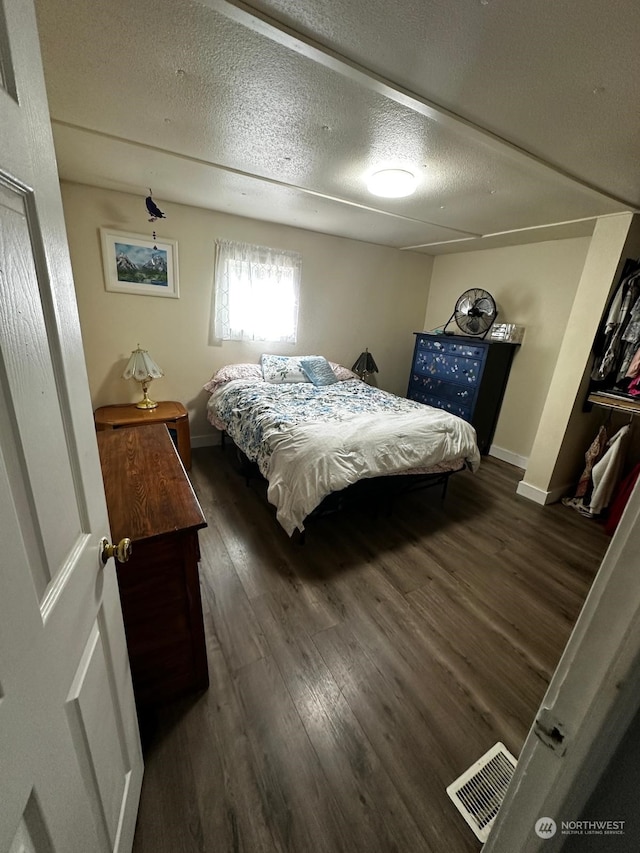 bedroom with dark hardwood / wood-style floors and a textured ceiling