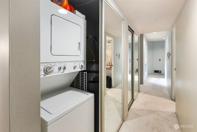 laundry room with light colored carpet and stacked washing maching and dryer