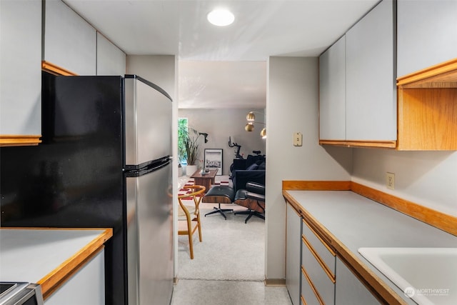 kitchen with stainless steel fridge, sink, and white cabinets