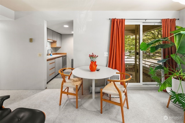 dining space featuring sink and light colored carpet