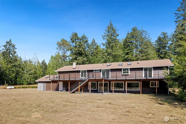 rear view of property featuring a wooden deck and a yard