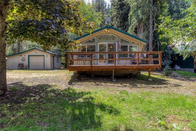 rear view of house featuring a garage, an outbuilding, driveway, and a deck