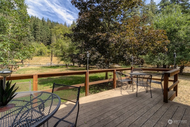 wooden deck with outdoor dining area and a lawn