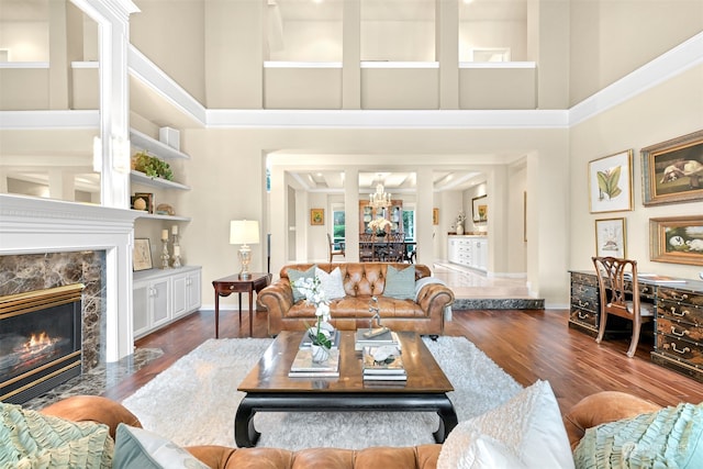 living room featuring hardwood / wood-style floors, built in shelves, a fireplace, and a high ceiling