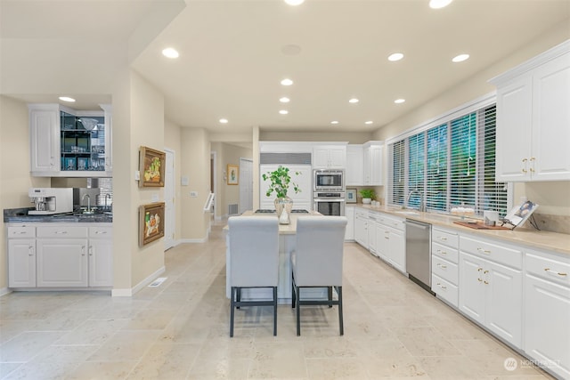 kitchen featuring appliances with stainless steel finishes, sink, a center island, white cabinetry, and a breakfast bar area