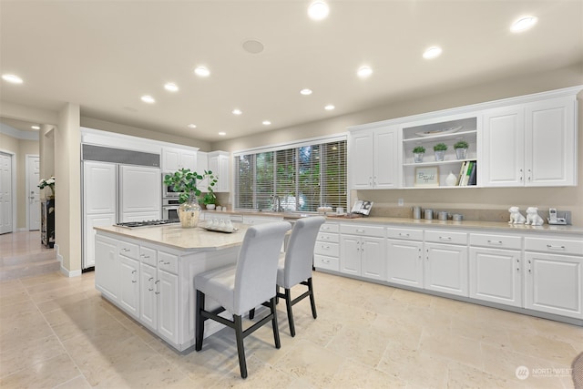 kitchen with appliances with stainless steel finishes, a center island, white cabinetry, and a kitchen breakfast bar