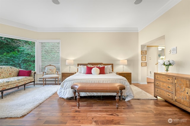 bedroom featuring hardwood / wood-style floors, baseboard heating, and crown molding