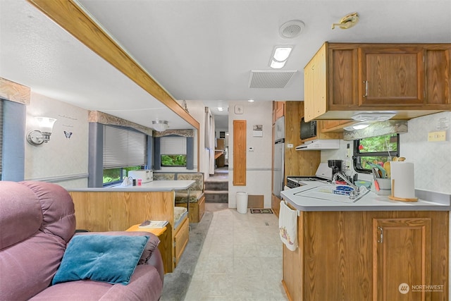 kitchen featuring kitchen peninsula, plenty of natural light, stove, and light tile patterned floors