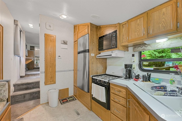 1056 Birch Ln, Sumas, WA 98266 - kitchen with gas stove, black microwave, under cabinet range hood, light countertops, and a sink