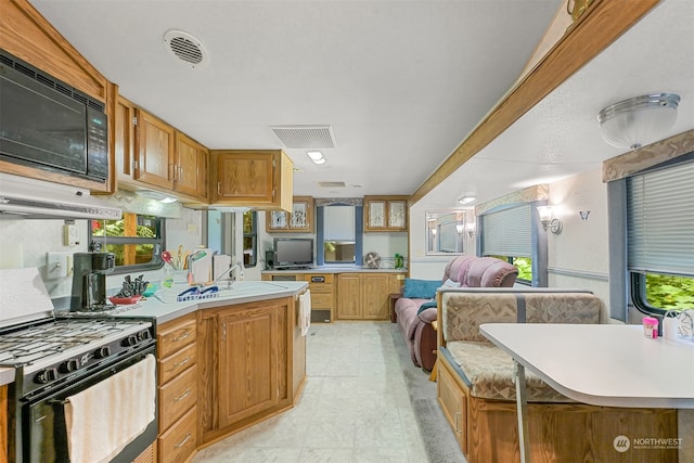 kitchen featuring black microwave, sink, range with gas stovetop, light tile patterned floors, and a kitchen island