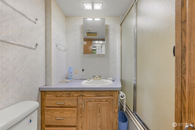 bathroom featuring an enclosed shower, vanity, and toilet