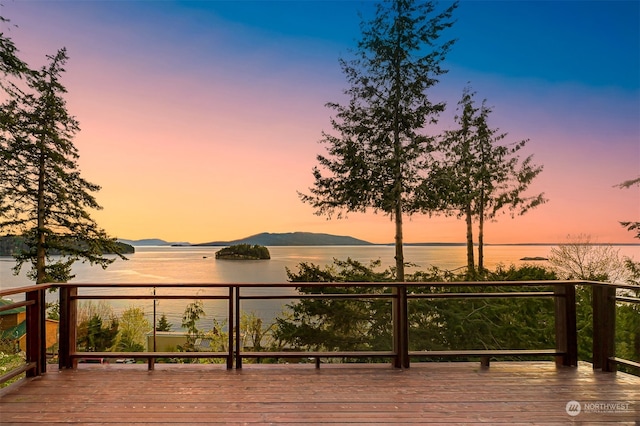 deck at dusk featuring a water view