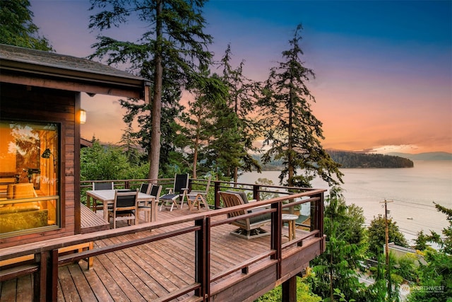 deck at dusk featuring a water view