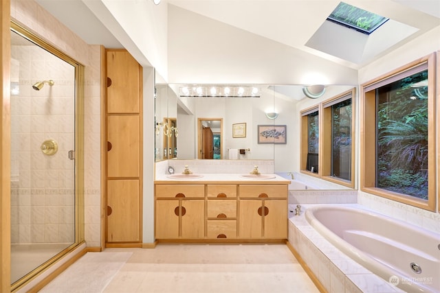 bathroom with separate shower and tub, lofted ceiling with skylight, double vanity, and tile patterned floors