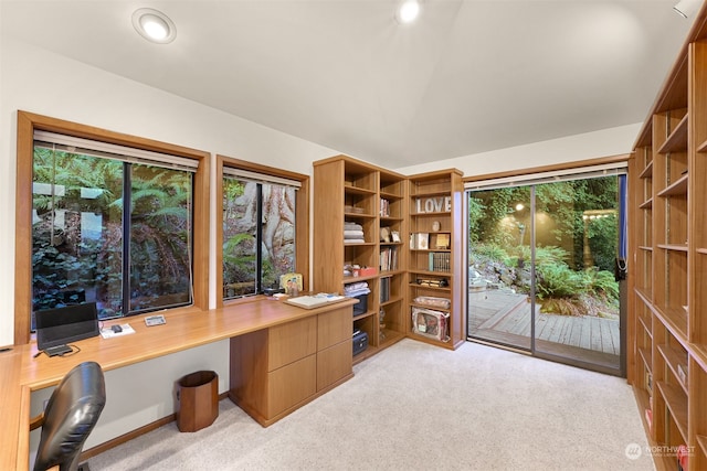 carpeted home office featuring vaulted ceiling and built in desk