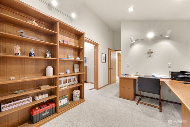 office featuring vaulted ceiling, rail lighting, light carpet, and built in desk