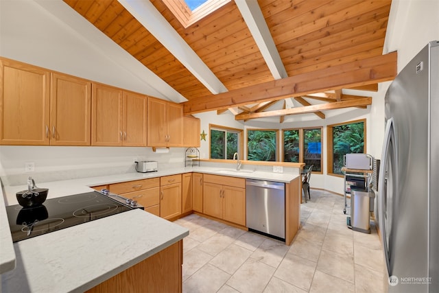 kitchen with beam ceiling, a skylight, light tile patterned floors, stainless steel appliances, and kitchen peninsula