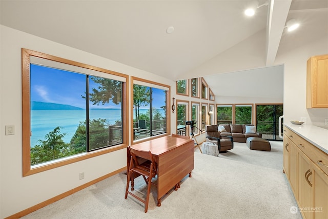 office space featuring light carpet, a water view, and lofted ceiling with beams