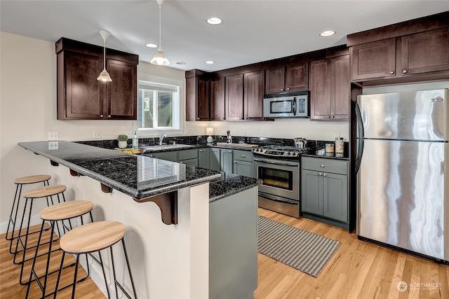 kitchen featuring light hardwood / wood-style flooring, kitchen peninsula, a kitchen breakfast bar, and appliances with stainless steel finishes