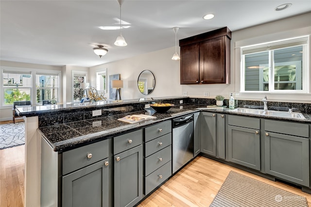 kitchen featuring dishwasher, decorative light fixtures, light wood-type flooring, sink, and kitchen peninsula