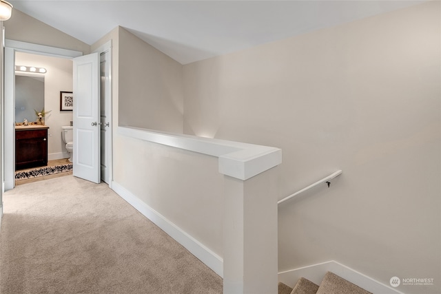 corridor featuring light colored carpet and vaulted ceiling