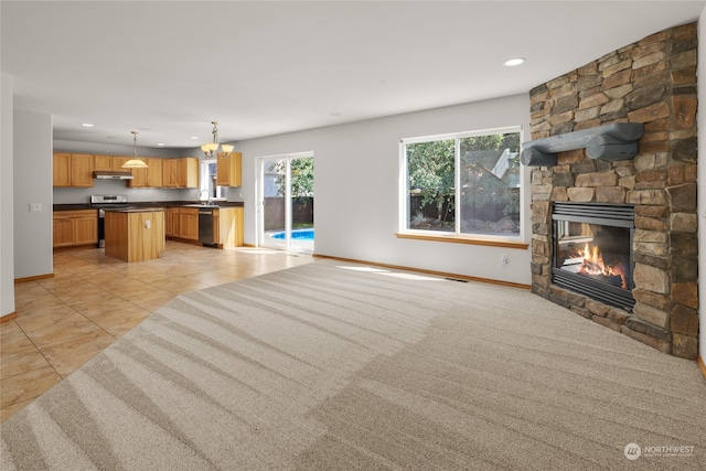 kitchen with a kitchen island, hanging light fixtures, dishwashing machine, light tile patterned floors, and a fireplace