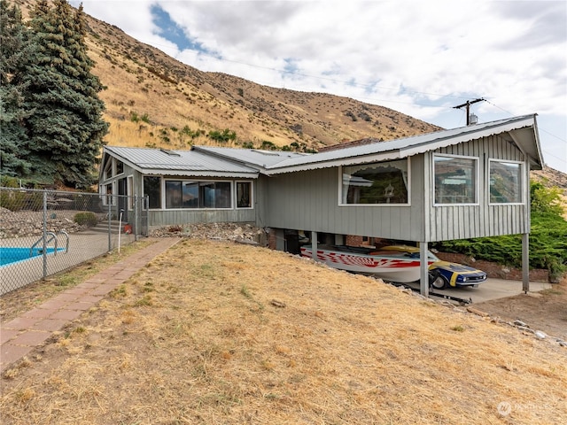 view of front of home with a sunroom, metal roof, fence, and a mountain view