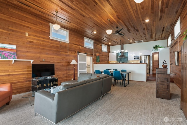 living area with light carpet, visible vents, a ceiling fan, wooden ceiling, and wood walls