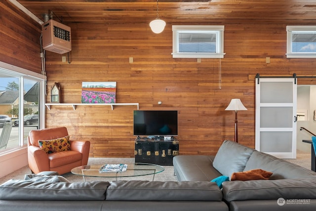 carpeted living room with a heating unit, wooden walls, and a barn door